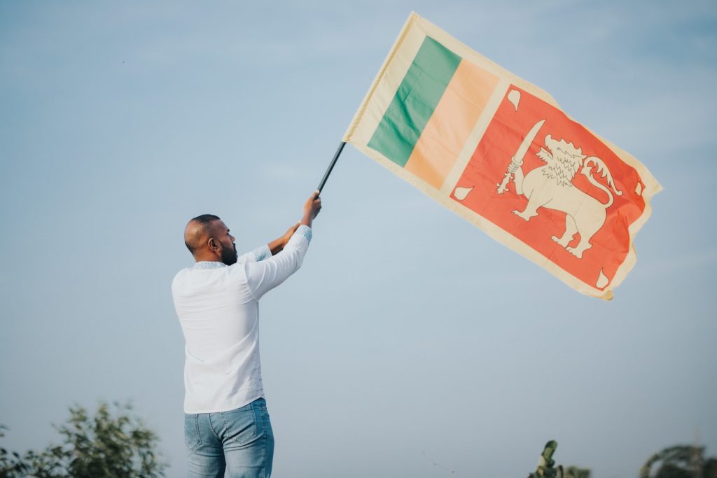 Un uomo che sventola la bandiera nazionale dello Sri Lanka